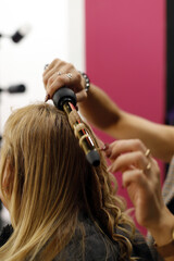 Fototapeta premium mano de peluquera peinando el pelo con maquina de rizos