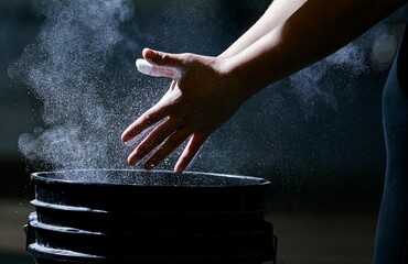 Closeup shot of hands with chalk for powerlifting at the gym on a dark background
