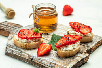 Crostini or toasts with strawberries and cream cheese ricotta. Delicious breakfast or snack, Clean eating, dieting, vegan food concept. top view
