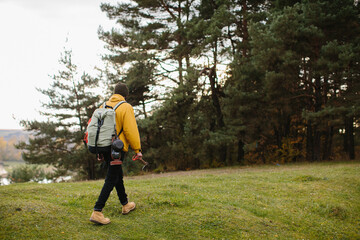 Naklejka na ściany i meble A hiker walking in nature carrying backpack
