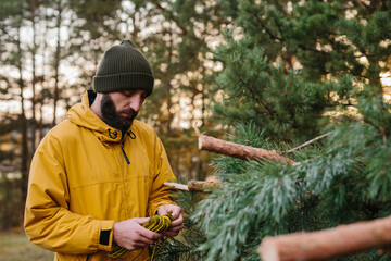 Man building a survival shelter in the forest. Shelter in the woods from pine branches.