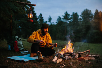 A lonely wanderer is having dinner in the mountains by a campfire.