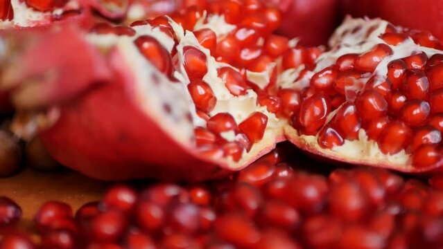 Lots of heaps of red ripe pomegranate seeds and parts of broken pomegranates close-up filling the entire frame of a dolly shot. Juices and cocktails from fresh ripe pomegranates