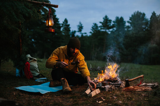 A lonely wanderer is having dinner in the mountains by a campfire.