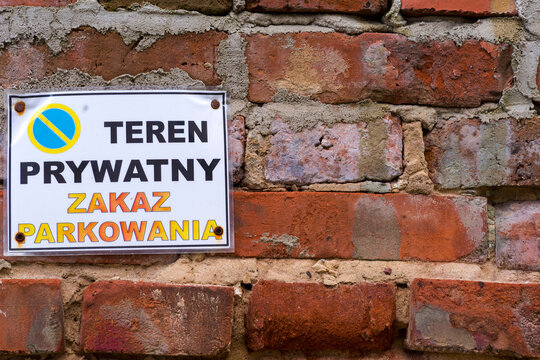 Fototapeta Stary mur z czerwonej cegły z wiszącą na nim plastikową tabliczką z napisem : TEREN PRYWATNY !! ZAKAŻ PARKOWANIA !!