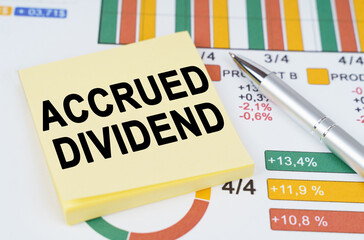 On the business charts are a pen and stickers with the inscription - ACCRUED DIVIDEND