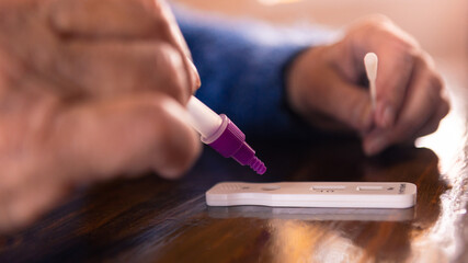 Old woman placing the sample into the covid-19 antigen diagnostic test device