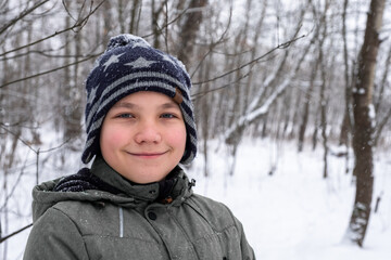 Fototapeta na wymiar portrait of a smiling boy on the background of a winter forest