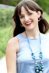 Beautiful young woman smiling at camera outdoors in a park.