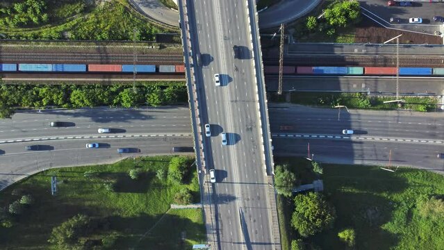4k Top view of cars drive on intersecting roads and railroad in city irrl. Above pic of transport rides on asphalt roads in area with railroad and green vegetation outdoors. Operator launches drone