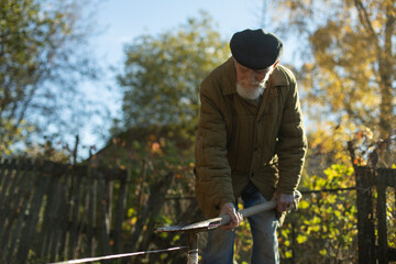 Russian old man in garden. Grandpa works on land. Pensioner works.