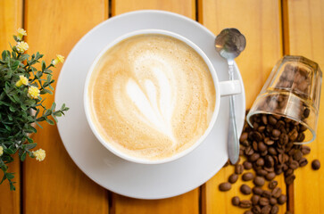 coffee cup with cream and heart with scattered coffee beans