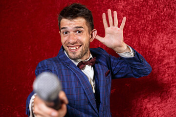 Smiling showman showing ear gesture and reaching out microphone while listening during performance...