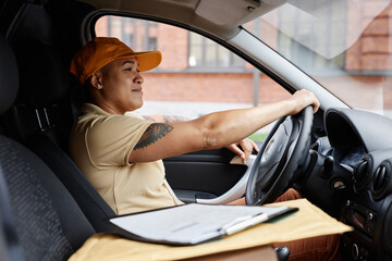 Side view portrait of young multiethnic woman driving delivery truck and wearing uniform