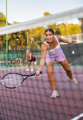 Female player playing tennis in tennis court outdoor behind the net