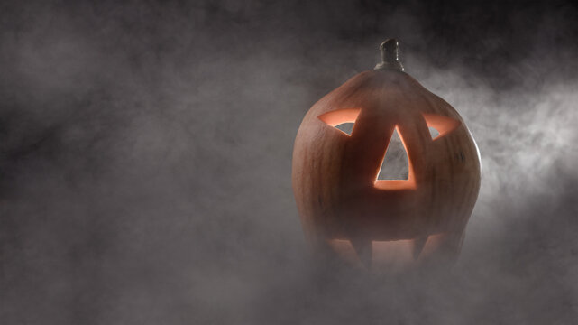 scary pumpkin head in a mystical haze. creative halloween concept with copy space. front side view