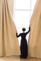 Woman by the window moving curtains