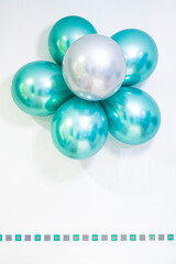 flower made of helium balloons in metallic colours green and silver, on a white background, copy space, green and silver squares valance