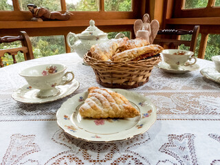 Tea time. Beautiful table with pastries (sfogliatella), teapot, tea cups and lace table cloth.