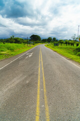 Fototapeta na wymiar Lonely road in Costa Rica with grassy sidewalks