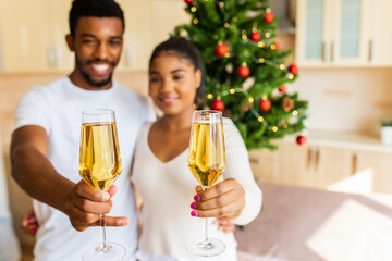 happy couple holding a glasses of champagne and celebrating new year at home