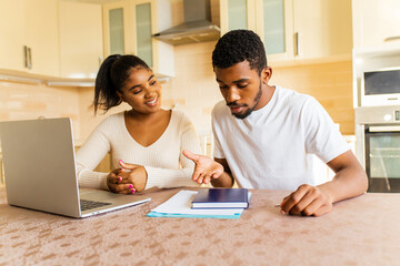 young couple sitting with laptop and education online at kitchen at home