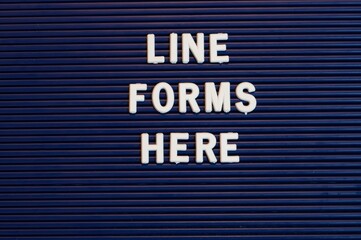 Pushboard sign that says line forms here in plastic letters