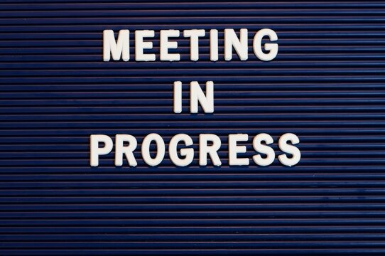 Pushboard sign that says meeting in progress in plastic letters