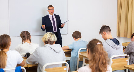 Male speaker giving lesson for teenage students in classroom