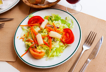 Mediterranean vegeterian salad served with carrot and onion on wooden table