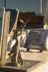 Bronze sculpture, woman with raised hands releasing a dove. Tribute on a grave