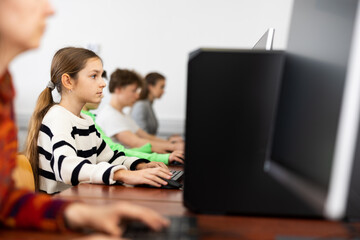 Young caucasian girl learning to use personal computer during lesson in school.