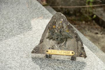 Funerary plaque in triangular stone decorated with birds, with the inscription: "To our father"