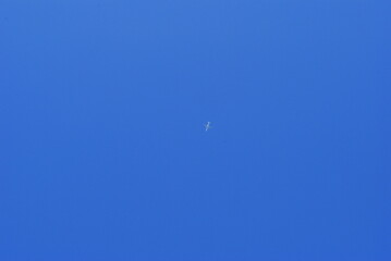 Obraz na płótnie Canvas White plane flying against a clear blue sky.