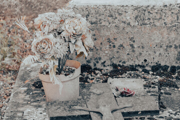 Cemetery, close-up of an ancient grave decorated with a time-worn flower pot and a cross and christ