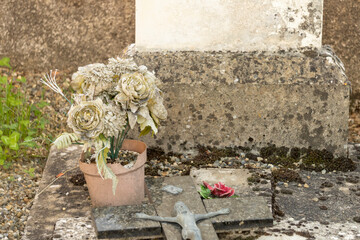Cemetery, close-up of an ancient grave decorated with a time-worn flower pot and a cross and christ
