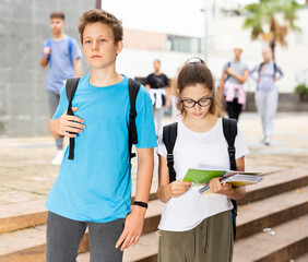 Two students holding bags and talking while walking