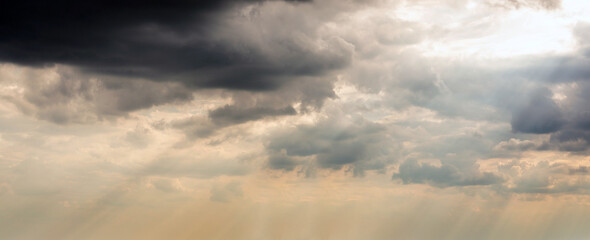 Dramatic Sky Background with sunny beams. Panoramic view of Stormy Clouds in Dark sky