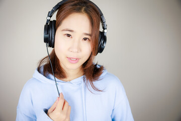 ヘッドフォンをつけて音楽を聴くアジア人女性