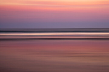 Panned image of a sunset reflected in the wet sand on a beach.  Intentional camera movement to blur...
