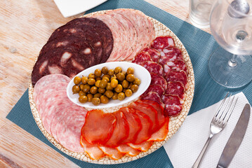 Slices of Spanish sausage, dry-cured loin, salami and morcilla served with green olives .