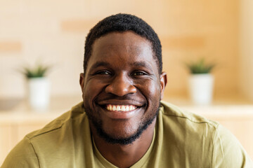 portrait of cheerful happy young man with in casual white t-shirt at home