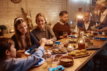 Happy extended Jewish family enjoying in meal at dining table on Hanukkah.