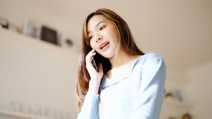 Happy young asian woman speaking on mobile phone at home, Female teen answering call on cellphone...