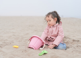 Expressive young girl is playing on the beach on a very foggy day