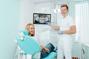 Doctor dentist and woman patient smilling in dental clinic. X-ray on digital screen in stomatology...