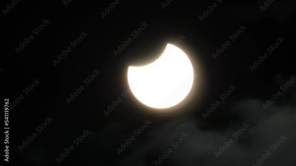 Wall mural partial solar eclipse with a small thin layer of clouds moving past the sun - oct. 25, 2022