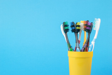 A set of toothbrushes in a yellow plastic cup on a blue background.