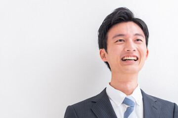 話をする若いスーツを着た日本人男性・白バック