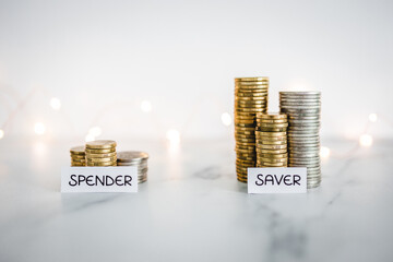 Saver vs spender texts in front of big and small stacks of coins. Concept  of money, abundance and...